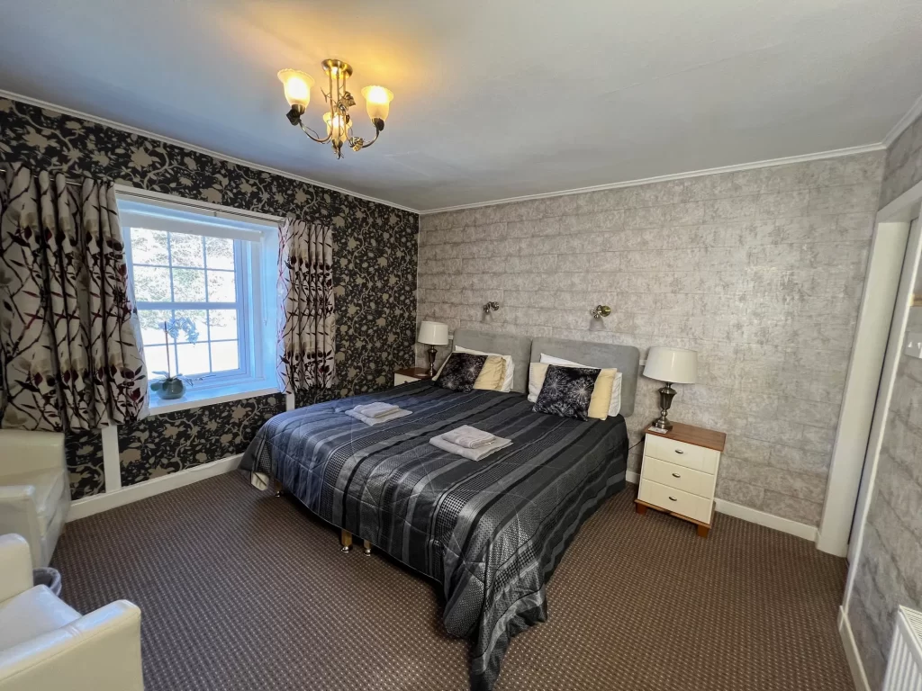 A cozy and traditional double and twin bedroom at The Old Inn, showing rustic wood furniture and soft lighting.