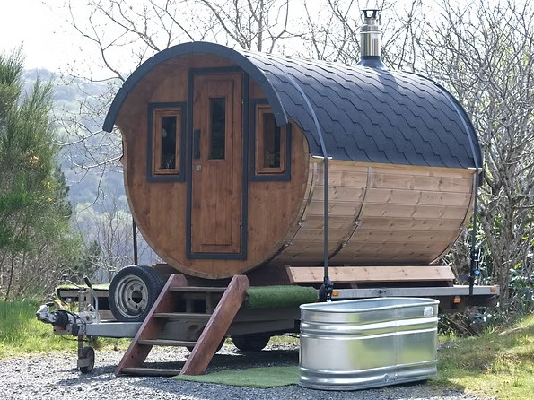 A traditional wood-burning mobile sauna situated outdoors, offering a relaxing "fire and ice" experience for winter guests.