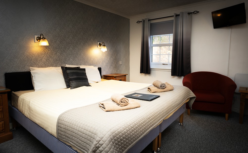 Modern dog-friendly accommodation at The Old Inn Gairloch, featuring a large bed, seating area, and views of the Highland landscape.